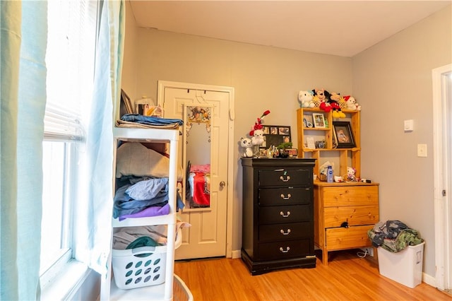 bedroom featuring multiple windows, baseboards, and light wood finished floors