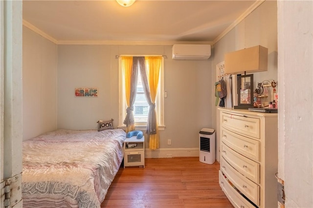 bedroom with ornamental molding, baseboards, light wood finished floors, and a wall mounted AC