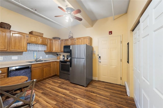 kitchen with a sink, a baseboard heating unit, light countertops, stainless steel appliances, and dark wood-style flooring