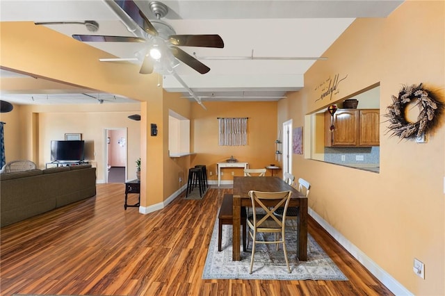 dining area featuring baseboards, beam ceiling, wood finished floors, and a ceiling fan