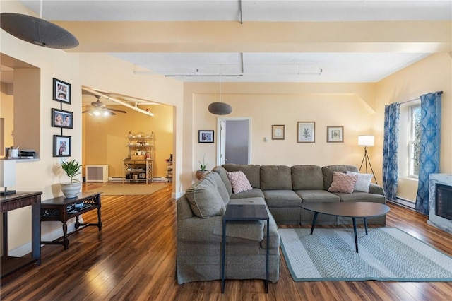 living area with beam ceiling, track lighting, a fireplace, and wood finished floors