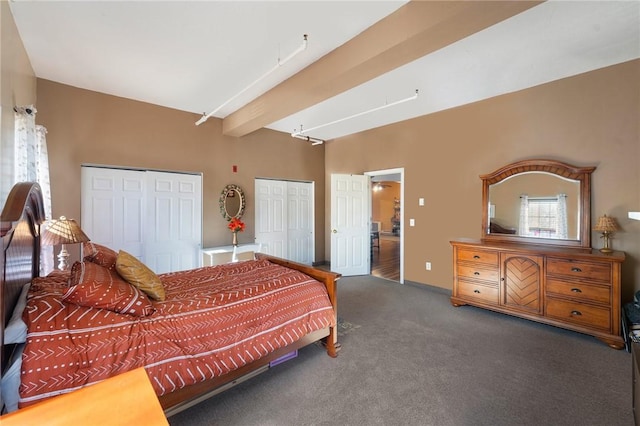 bedroom featuring beamed ceiling, multiple closets, and carpet floors