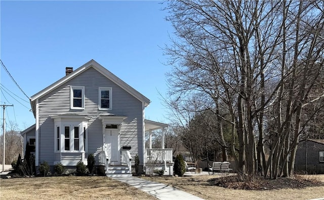 view of front of house featuring a front yard, covered porch, and a chimney