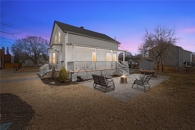 back of property with a storage unit, a patio, fence, a fire pit, and an outdoor structure