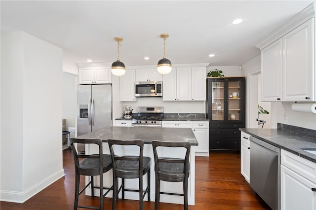 kitchen with dark countertops, white cabinetry, stainless steel appliances, and dark wood-style flooring