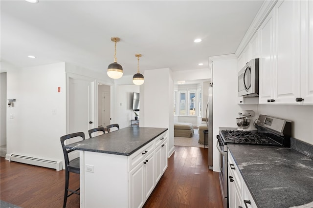 kitchen featuring dark wood-style floors, a baseboard radiator, a breakfast bar, white cabinets, and appliances with stainless steel finishes