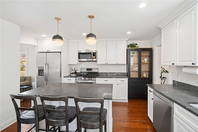 kitchen featuring recessed lighting, dark wood-type flooring, appliances with stainless steel finishes, white cabinetry, and a kitchen breakfast bar