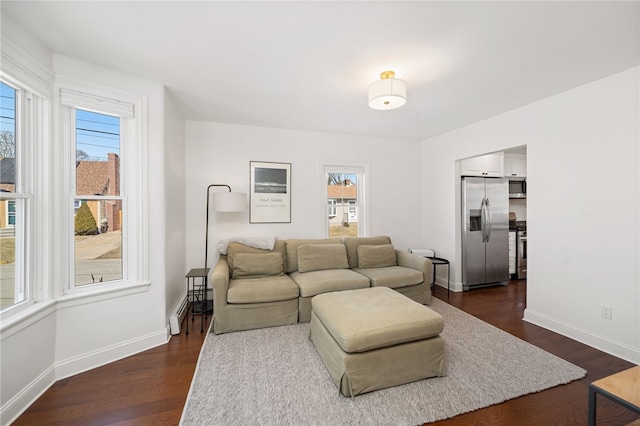 living area featuring dark wood-style floors, a healthy amount of sunlight, and baseboards