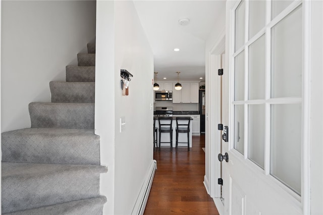 stairs with recessed lighting, wood finished floors, and a baseboard radiator