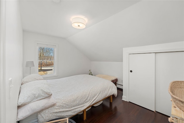 bedroom featuring a baseboard radiator, a closet, dark wood-style floors, and vaulted ceiling