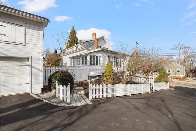 view of front of home with a garage, a fenced front yard, and a chimney