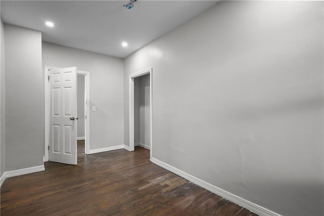 empty room with dark wood-type flooring, recessed lighting, and baseboards