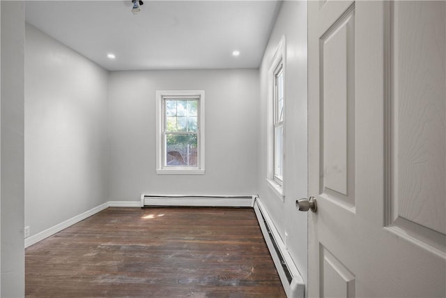 spare room featuring a baseboard heating unit, baseboards, baseboard heating, recessed lighting, and wood finished floors