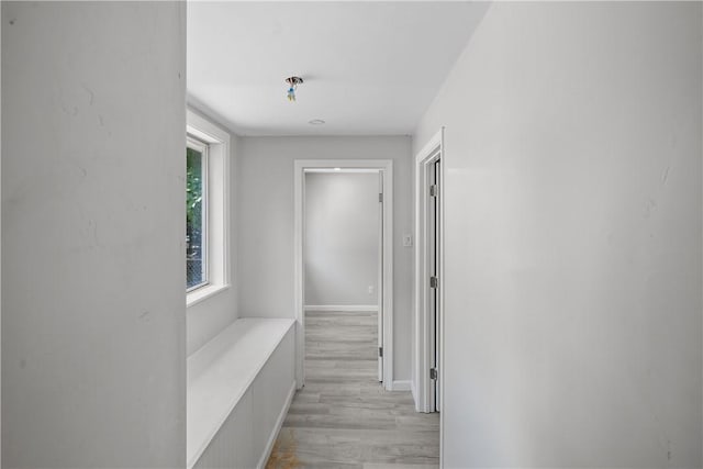 hall featuring baseboards and light wood-type flooring