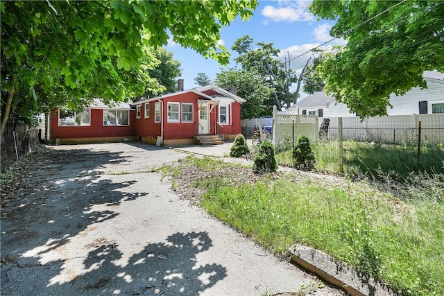 bungalow featuring driveway, fence, a chimney, and entry steps