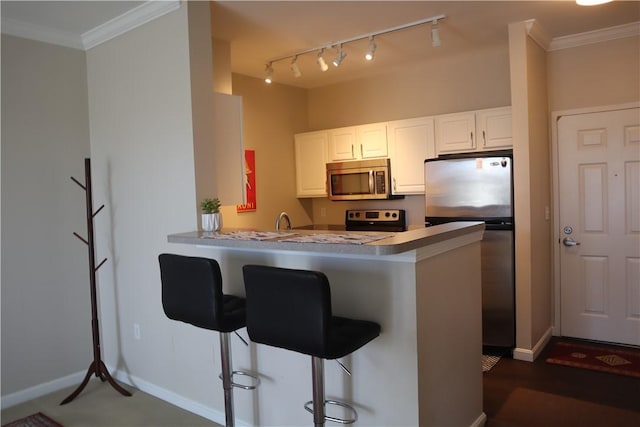 kitchen featuring a kitchen breakfast bar, stainless steel appliances, crown molding, and a peninsula