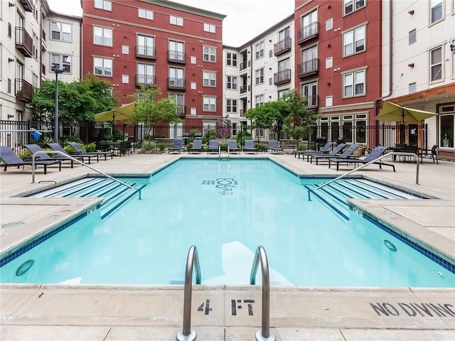 view of swimming pool featuring a patio and fence