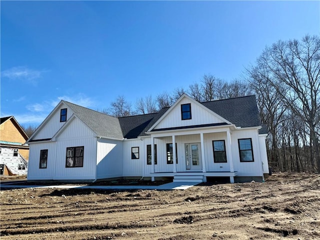 modern farmhouse featuring covered porch and roof with shingles