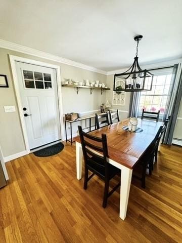 dining room with baseboards, wood finished floors, ornamental molding, and a chandelier