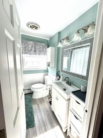 full bathroom with visible vents, toilet, wood finished floors, shower / bath combination with curtain, and vanity