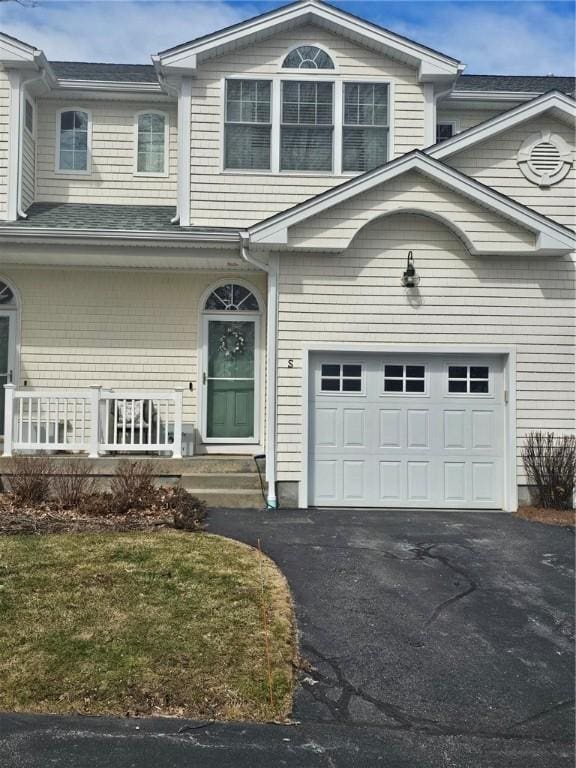 traditional-style house featuring a porch, driveway, and a garage