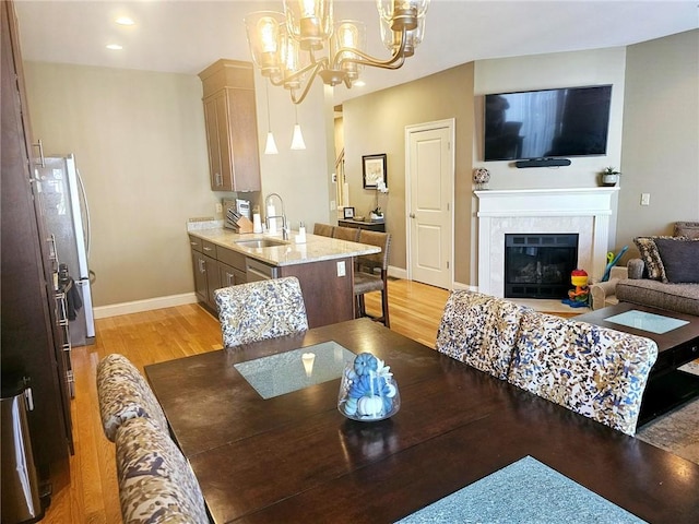 dining room featuring a fireplace, light wood-style floors, baseboards, and a chandelier