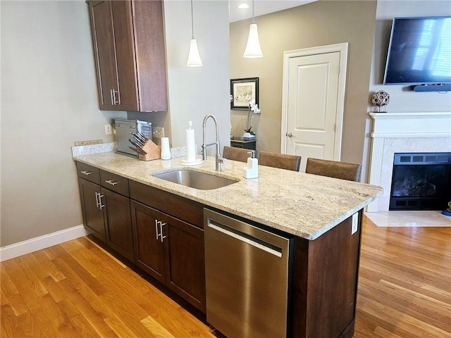 kitchen with a sink, dark brown cabinets, dishwasher, and light wood finished floors