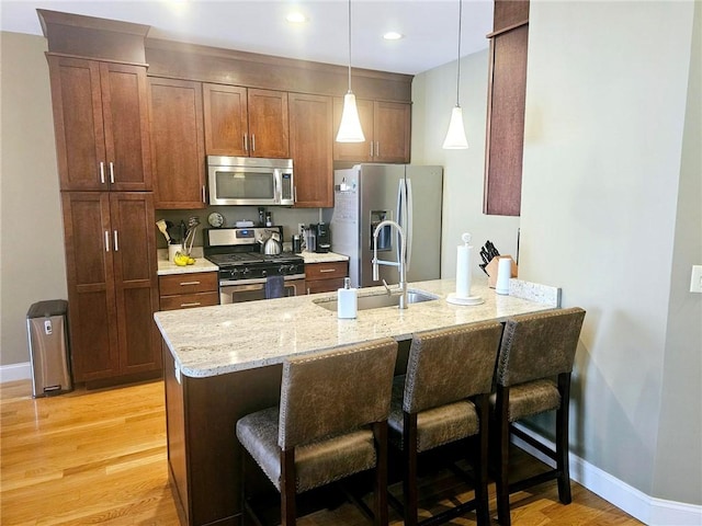 kitchen featuring a breakfast bar, a peninsula, appliances with stainless steel finishes, and a sink