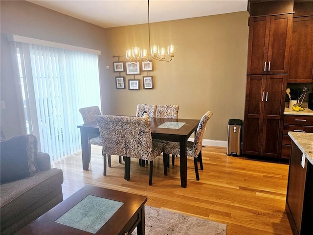 dining area featuring a chandelier, light wood-type flooring, and baseboards