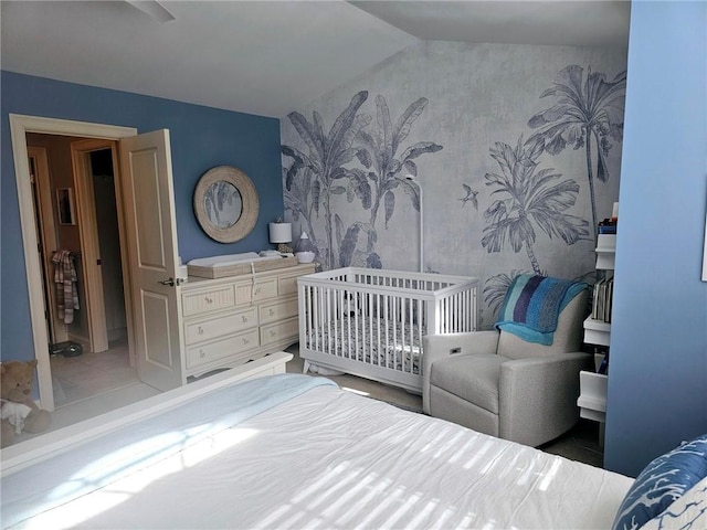 bedroom with wallpapered walls, lofted ceiling, and a crib