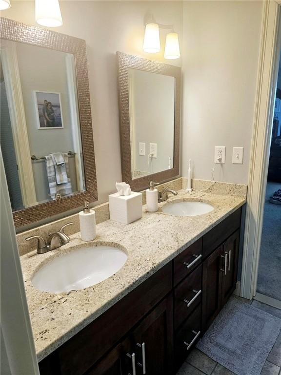 full bath featuring a sink, double vanity, and tile patterned flooring