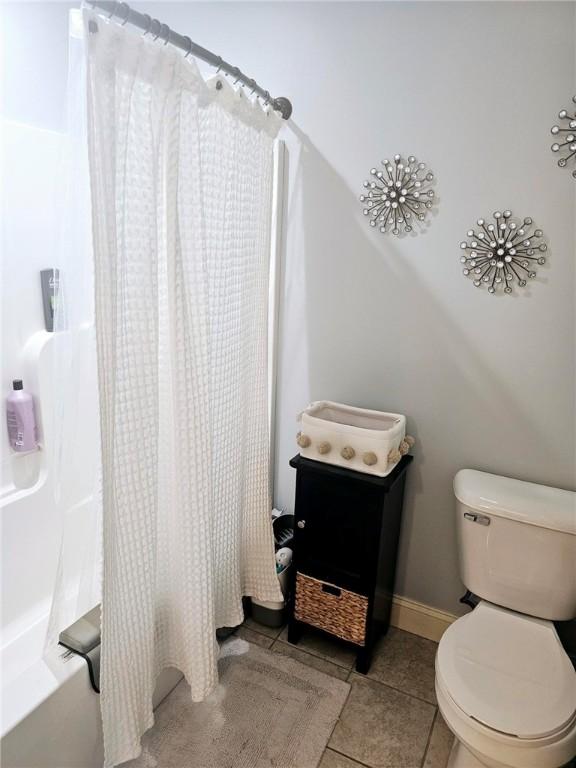 bathroom with tile patterned floors, baseboards, and toilet