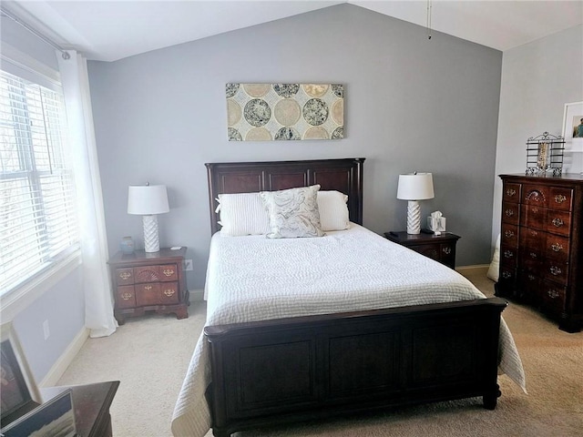 bedroom featuring lofted ceiling, light colored carpet, and baseboards