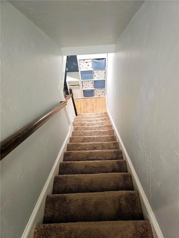 staircase featuring baseboards and a textured wall