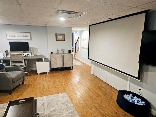 home theater room featuring visible vents, a paneled ceiling, baseboards, and light wood-style flooring