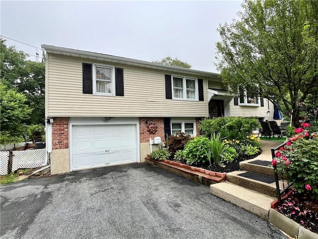 split foyer home with aphalt driveway, brick siding, and a garage