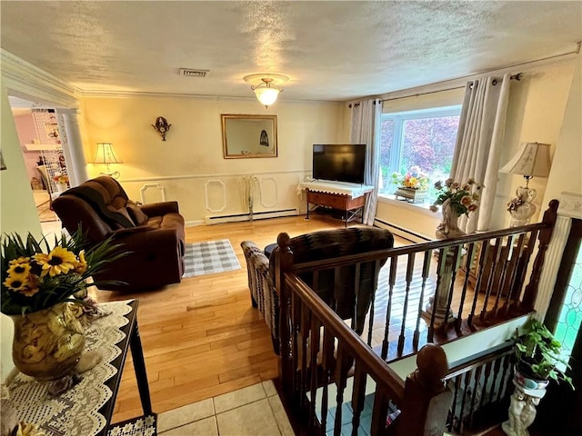 living area featuring visible vents, a baseboard radiator, ornamental molding, a textured ceiling, and light wood-type flooring