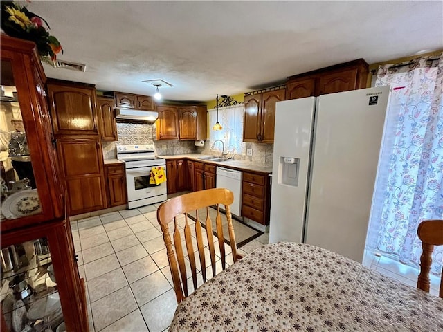 kitchen featuring white appliances, light tile patterned floors, visible vents, a sink, and under cabinet range hood