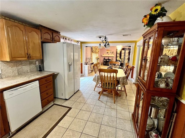 kitchen with visible vents, backsplash, tile countertops, light tile patterned floors, and white appliances