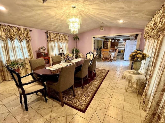 dining area with a textured ceiling, a notable chandelier, light tile patterned flooring, and vaulted ceiling