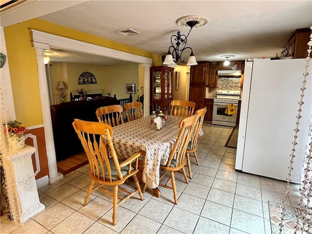 dining space featuring light tile patterned floors, visible vents, a notable chandelier, and ornate columns