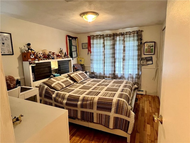 bedroom featuring baseboard heating and wood finished floors