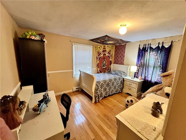 bedroom featuring baseboard heating, a textured ceiling, light wood-type flooring, and baseboards