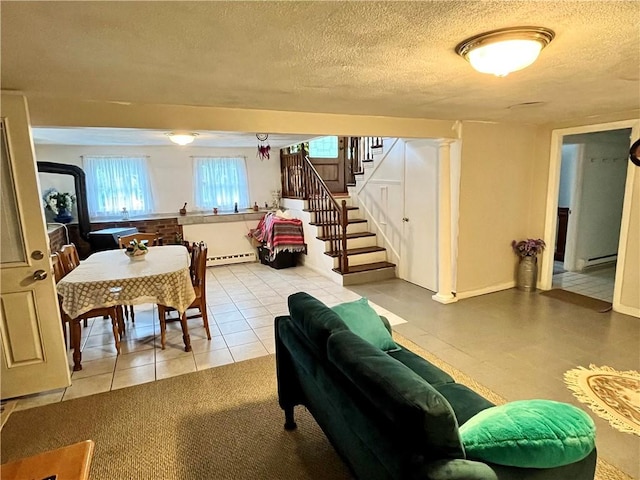 interior space with stairway, baseboard heating, a textured ceiling, and a baseboard heating unit