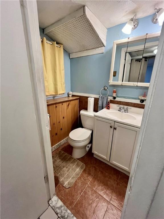 bathroom featuring toilet, vanity, and a textured ceiling