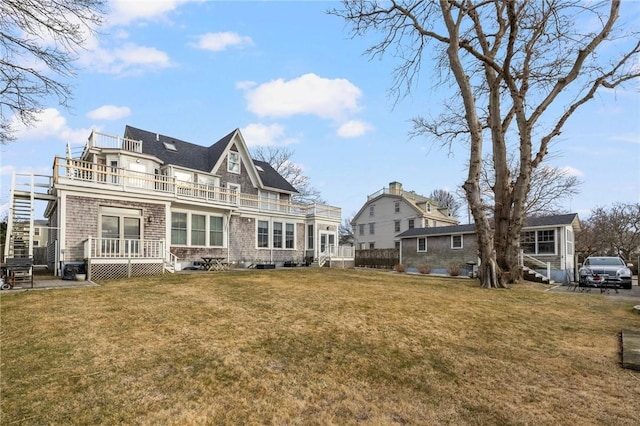 rear view of house featuring a balcony and a lawn