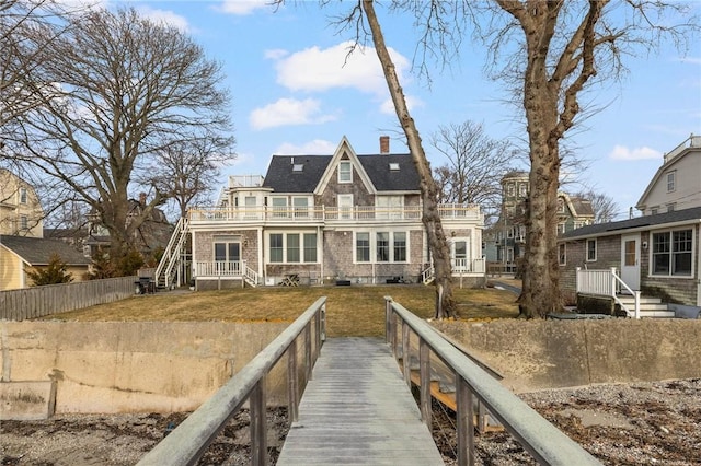 back of property with a balcony, fence, a lawn, and a chimney