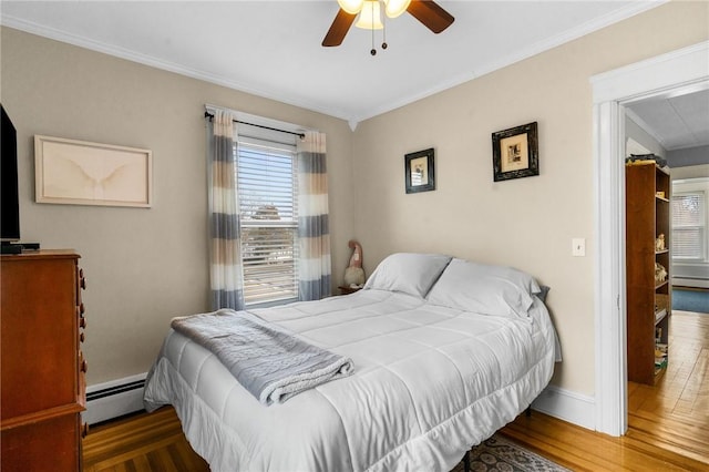 bedroom featuring a baseboard radiator, baseboards, wood finished floors, and ornamental molding