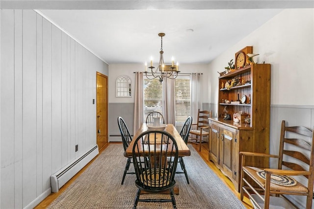 dining space with light wood-type flooring, a baseboard radiator, and a notable chandelier