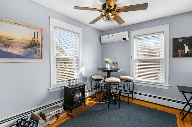 dining space featuring a wealth of natural light, baseboard heating, a wall mounted air conditioner, and a wood stove